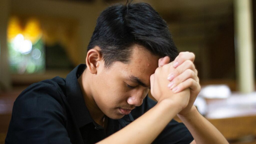 Homem com a cabeça baixa e mãos unidas em oração, expressando arrependimento e busca sincera por Deus