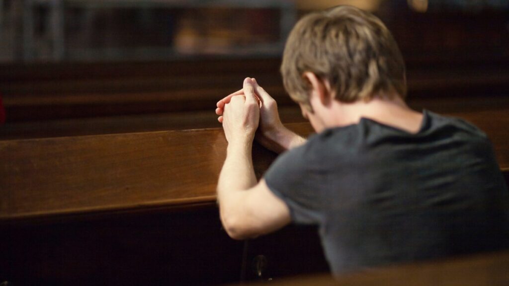 Homem ajoelhado orando na igreja simbolizando arrependimento em esboço de pregação 2 Crônicas 7:14