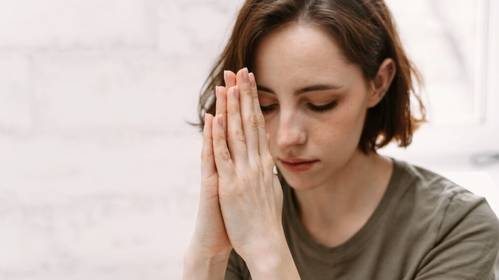 Mulher orando com mãos juntas simbolizando fé em esboço de pregação Isaías 43:13